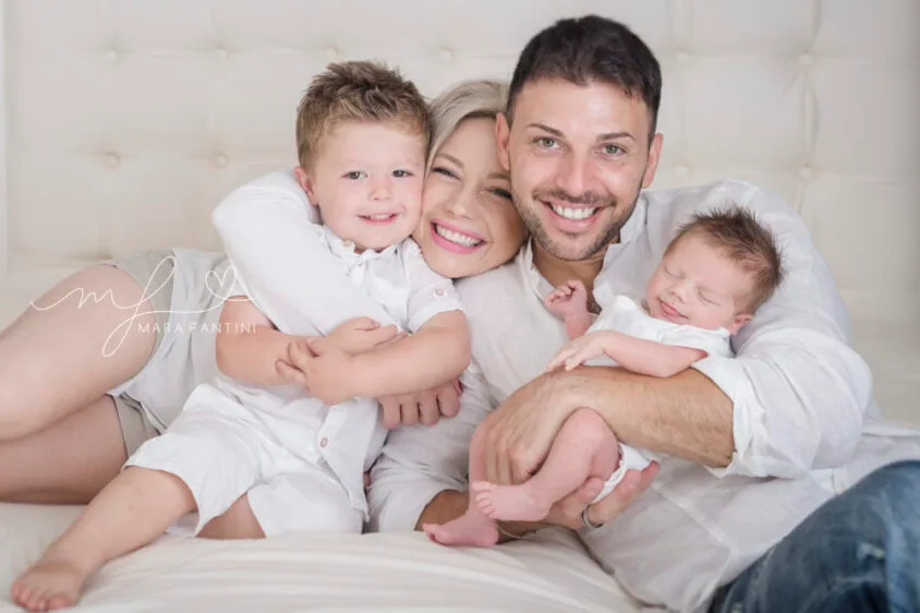 Famiglia sul letto: mamma, papà e i loro due bambini durante un servizio fotografico a Roma