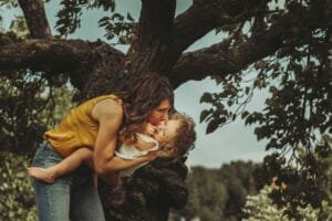 Mamma bacia la sua bambina sotto un grande albero al Parco degli Acquedotti, Roma