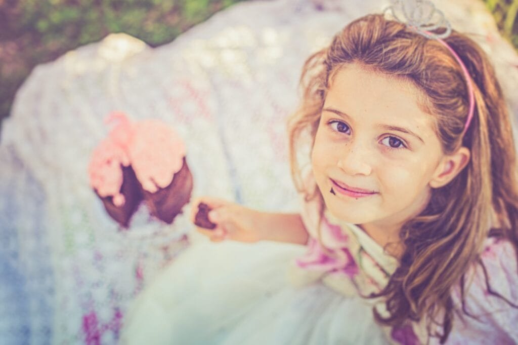 Primo piano della bambina che assaggia un dolcetto al cioccolato durante il compleanno al parco